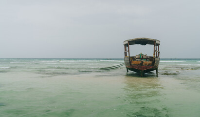 Shallow atoll sandbanks with lonely fisherman boat on low tide Nungwi beach in the Indian Ocean on the Zanzibar island, Tanzania. Exotic countries traveling concept image.