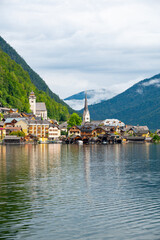 Fototapeta na wymiar Hallstatt Village and Hallstatter See lake in Austria. Scenery with famous old church near the lake. Clouds and mist over the mountains in background. Famous tourist destination.