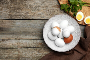 Flat lay composition with boiled eggs on wooden table. Space for text