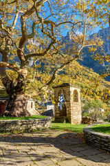 Taxiarchon stone bell tower   church  during  fall season in the picturesque village of Mikro  papigo in Epirus zagori greece