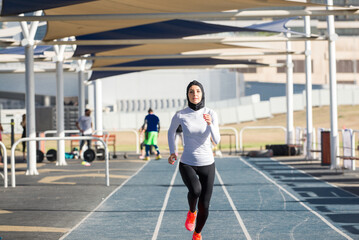 Arabian woman with typical muslim dress training outdoors in Dubai - Middle-eastern beautiful female adult doing fitness outside