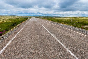 Asphalt road in polar tundra landscape. Far North of Russia