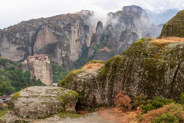 Scenic view of Holy Monastery of Rousanos appearing from the fog, Kalambaka, Meteora, Thessaly, Greece, Europe. Mystical atmosphere in dramatic landscape. Landmark build on unique rock formations