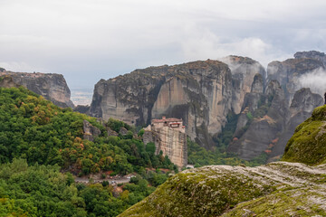 Fototapeta na wymiar Scenic view of Holy Monastery of Rousanos appearing from the fog, Kalambaka, Meteora, Thessaly, Greece, Europe. Mystical atmosphere in dramatic landscape. Landmark build on unique rock formations