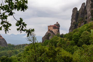 Fototapeta na wymiar Scenic view of Holy Monastery of St Nicholas Anapafsas seen from forest on cloudy day, Kalambaka, Meteora, Thessaly, Greece, Europe. Dramatic landscape. Landmark build on unique rock formations