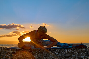 Young woman practicing yoga on the beach at sunrise. Harmony, wellbeing, meditation, healthy lifestyle, relaxation, yoga, self care, mindful meditation concept.
