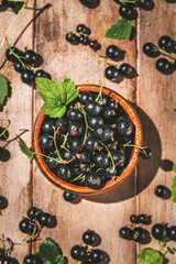 black currants in a bowl on a wooden background. berries, summer, vitamins, healthy natural food. top view. selective focus
