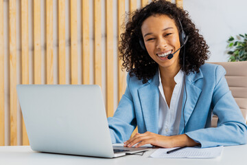 Businesswoman sitting at computer desk in the office with microphone headset