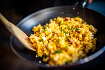 cooking tasty scrambled eggs with bacon in frying pan