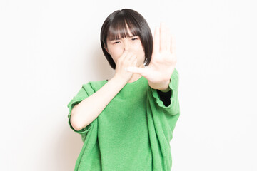 悪臭に困って鼻をつまんでいる若い女性