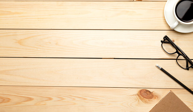 Top view office table desk. Workspace with blank, office supplies, pencil, green leaf, and coffee cup on wood background.