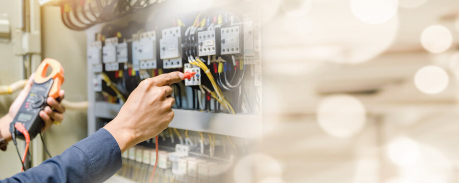 Electrician engineer work  tester measuring  voltage and current of power electric line in electical cabinet control.