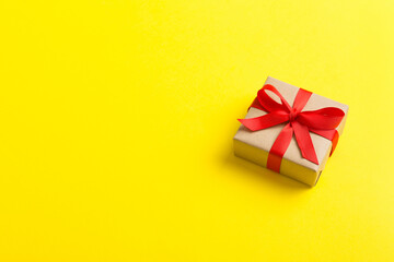 Wrapped christmas or other holiday handmade present in craft paper with colored ribbon. Present box, decoration of gift on table, top view with copy space