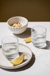 glass with water and lemon on plate on table