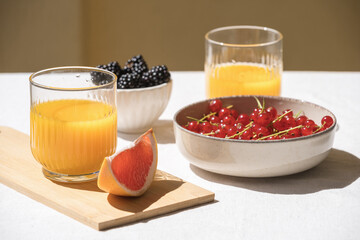 glass with juice and bowl with fresh berry on table