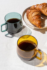 two cups with coffee and sweet croissants on plate on table indoors