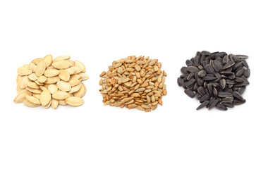 Three piles of pumpkin and sunflower seeds.