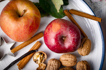 Reife Äpfel mit Walnüssen um Zimtstangen auf dem Teller