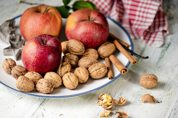 Reife &Auml;pfel mit Waln&uuml;ssen um Zimtstangen auf dem Teller