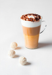 Latte macchiato in a tall glass on a white background. Cafe latte layered with milk in a high drinking glass. Minimalism. Сopy space