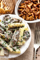 Macaroni with mushrooms and a raw chanterelle in bowl.