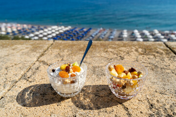 Fruit salad with Greek yogurt for breakfast in a hotel room on a balcony overlooking the sea
