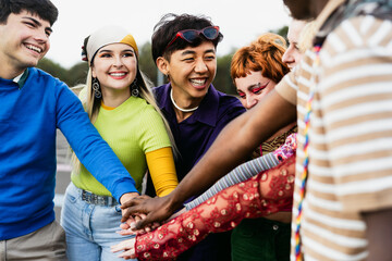 Happy young diverse friends having fun stacking hands together outdoor - Youth people millennial generation concept
