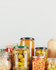 Autumn seasonal pickled or fermented vegetables and mushrooms in jars placed in row on a blue background with copy space. Fall home food preserving or canning. Vegetarian and vegan foods, close up