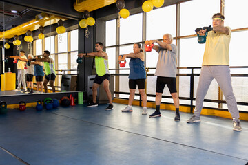 Men and woman exercising at health club with kettle bell on floor
