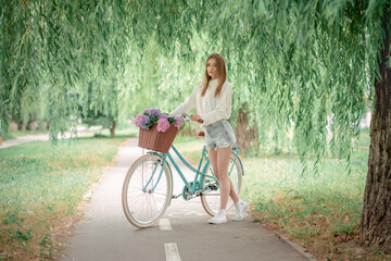 beautiful fair-haired girl on a bicycle with flowers. Hydrangeas. Nature