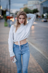 a girl in a white sweater is walking around the city