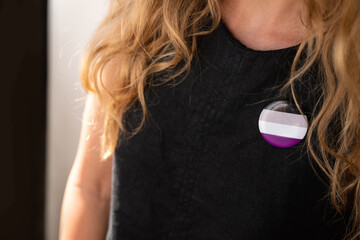 Woman with axexual badge puts on a shirt.