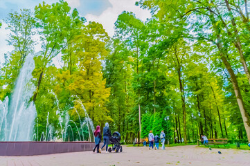 People walk in the park near the fountain