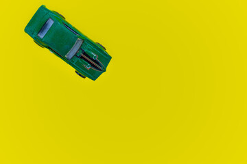 green toy car isolated on yellow background. top view with copy space