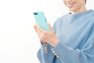 スマホを笑顔で使う中年女性の手元　白背景