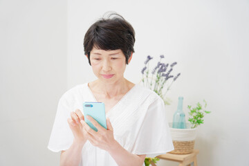 Fototapeta premium リビングでスマホを真顔で使う女性