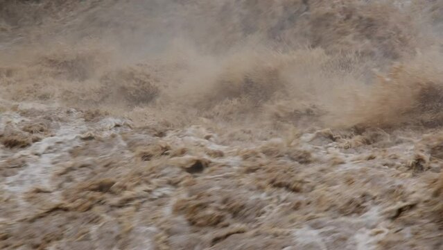 Waterfall cataract in forest mountains. Dirty streams are flowing down the mountain slopes of the mountain forest after heavy rains in Thailand. River flood, selective focus.