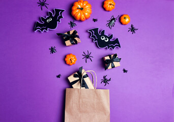 Brown paper shopping bag with Halloween decorations on purple background.