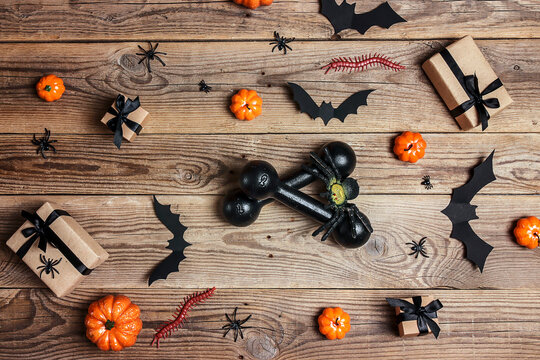 Вumbbells with Halloween decorations on old wooden boards.