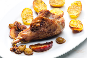 poultry leg baked with fruit and walnuts served with fried potatoes