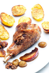 poultry leg baked with fruit and walnuts served with fried potatoes