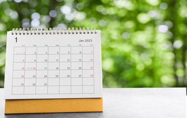 January 2023 desk calendar for planners and reminders on a black table on the natural background green .