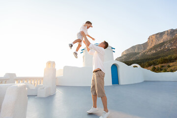 Father throws his son into the air at sunset. on the island of Santorini, Greece.