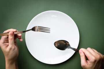 Woman hand holding spoon and fork with white plate which read for eating for breakfast, lunch and...