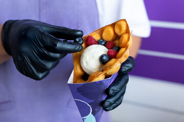 The chef decorates the Hong Kong bubble waffle with ice cream berries.