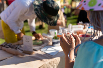 Obraz na płótnie Canvas Hands of a child sculpt clay dishes at a fair.