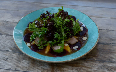 Salad with pulled duck, almond nuts and orange on a wooden background.
