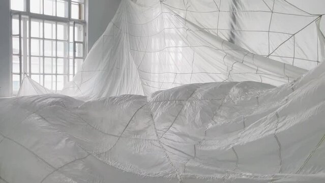 Art installation with the white parachute moving in the wind in the spacious studio.