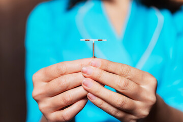 female contraceptive spiral in the hands of a nurse. device forbidding the birth of a child in a woman's hand. a medical device that prevents the fertilization of an egg. anticonception for girls