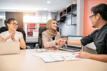 business muslim asian woman and man meeting. beautiful woman shake hand man for organization success plan talking to partner team. diversity employee sitting having convention celebrate by handshake